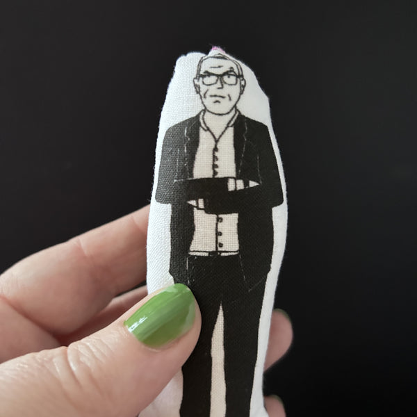 Mini fabric doll featuring an illustration of Taskmaster host Greg Davies. Greg is held up in a hand.