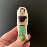 Mini illustrated fabric doll of Andrew Scott held in a hand against a black backdrop.