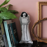 Chimamanda Adiche monochrome fabric doll on a shelf with feminist books and house plant