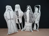 Four black and white fabric dolls featuring a screen printed illustration of The Great British Bake Off hosts and judges, Paul Hollywood, Prue Leith, Alison Hammond and Noel Fielding.