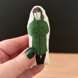 Mini illustrated fabric doll gift featuring Oasis frontman, Liam Gallagher, held in a hand for scale.