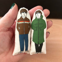 Mini illustrated fabric doll gift featuring Oasis brothers, Noel and Liam Gallagher, held in a hand for scale.