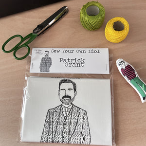 Sew Your Own Patrick Grant doll kit on a wooden surface and surrounded by craft supplies.