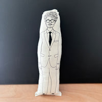 Black and white illustrated fabric cushion doll featuring actor Richard Ayoade.