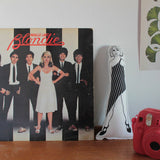 Debbie Harry monochrome fabric doll on a desk next to a Blondie vinyl album and instax camera