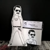 A black and white fabric doll and craft kit. Both feature an illustrated Freddie Mercury design. Against a black backdrop.