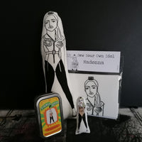 A selection of illustrated gifts featuring Madonna including a mini fabric doll and tin, a black and white doll and a craft kit.