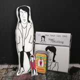 A selection of Noel Fielding gifts. A fabric doll, a mini fabric doll and tin, and a craft kit.