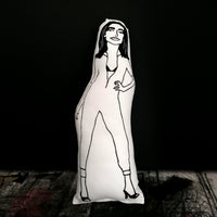 Black and white fabric doll of British singer songwriter PJ Harvey. Set against a black background.