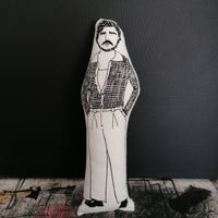 Black and white illustrated fabric doll of Pedro Pascal against a black wall.