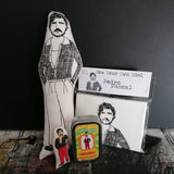 A selection of gifts featuring an illustration of Pedro Pascal. A black and white screen printed fabric doll, a mini doll and tin and a craft kit.
