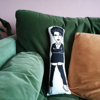 Black and white screen printed fabric cushion with Robert Smith design. The cushion is on a green velevet sofa against a pink wall.