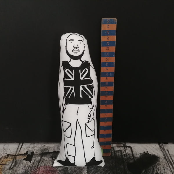 Black and white fabric screen printed cushion doll featuring an illustration of Stormzy. Stood beside a wooden ruler for scale.