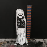 Black and white fabric screen printed cushion doll featuring an illustration of Stormzy, beside a wooden ruler for scale.