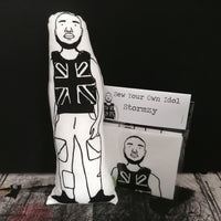 Black and white fabric screen printed cushion doll featuring an illustration of Stormzy and a craft kit.