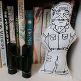 David Attenborough monochrome fabric doll on a bookshelf with nature books and binoculars