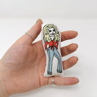 Mini doll of Dolly Parton held in a hand