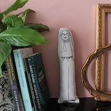 Gloria Steinem monochrome fabric doll on a shelf with feminist books , a plant and empty gilt frames