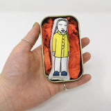 Mini doll of Greta Thunberg in a tin held in a hand