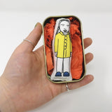 Greta Thunberg mini doll in a tin held in an open hand