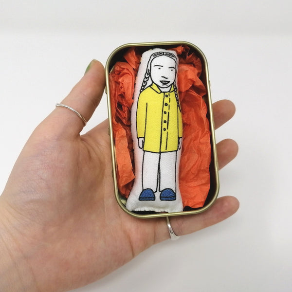 Mini doll of climate activist Greta Thunberg in a tin and held in and open hand
