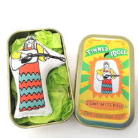 Mini doll of Joni Mitchell in a tin on a white background